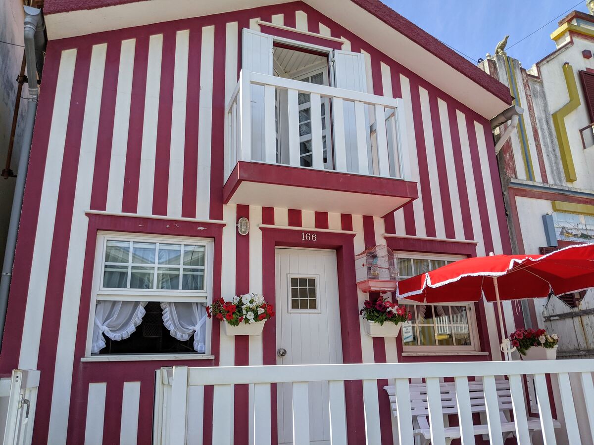 Image: The photo shows a house facade with red candy stripes in Costa Nova, Ilhavo, Portugal